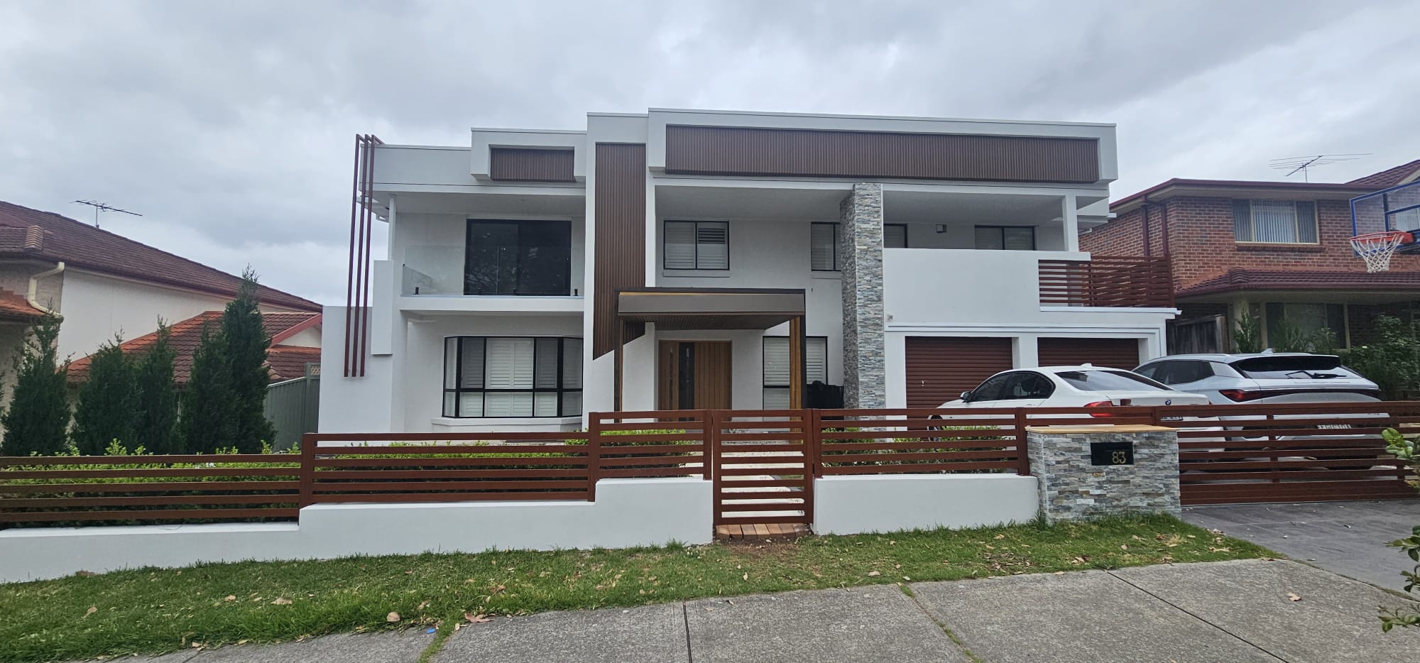 Modern two-storey home exterior with stone cladding and timber screens