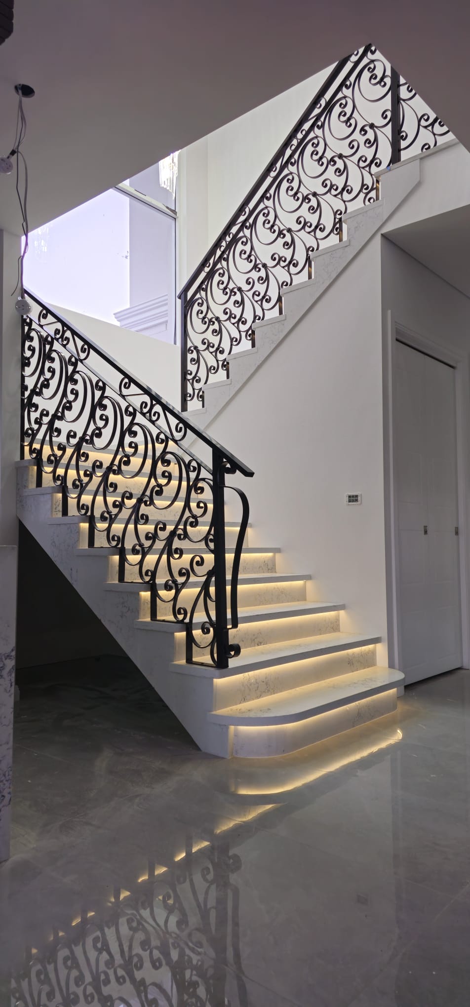 Elegant staircase with decorative wrought iron balustrade and LED step lighting