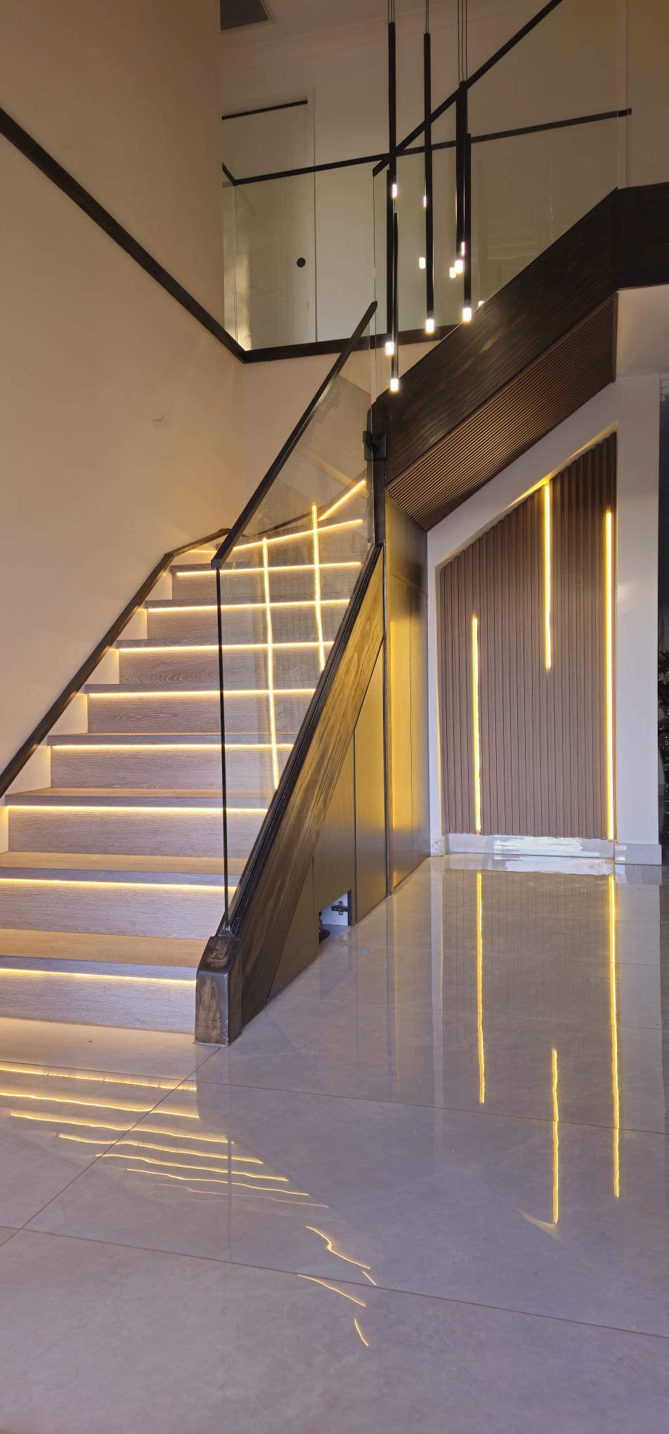 Modern staircase with LED step lighting, glass balustrade and pendant chandelier